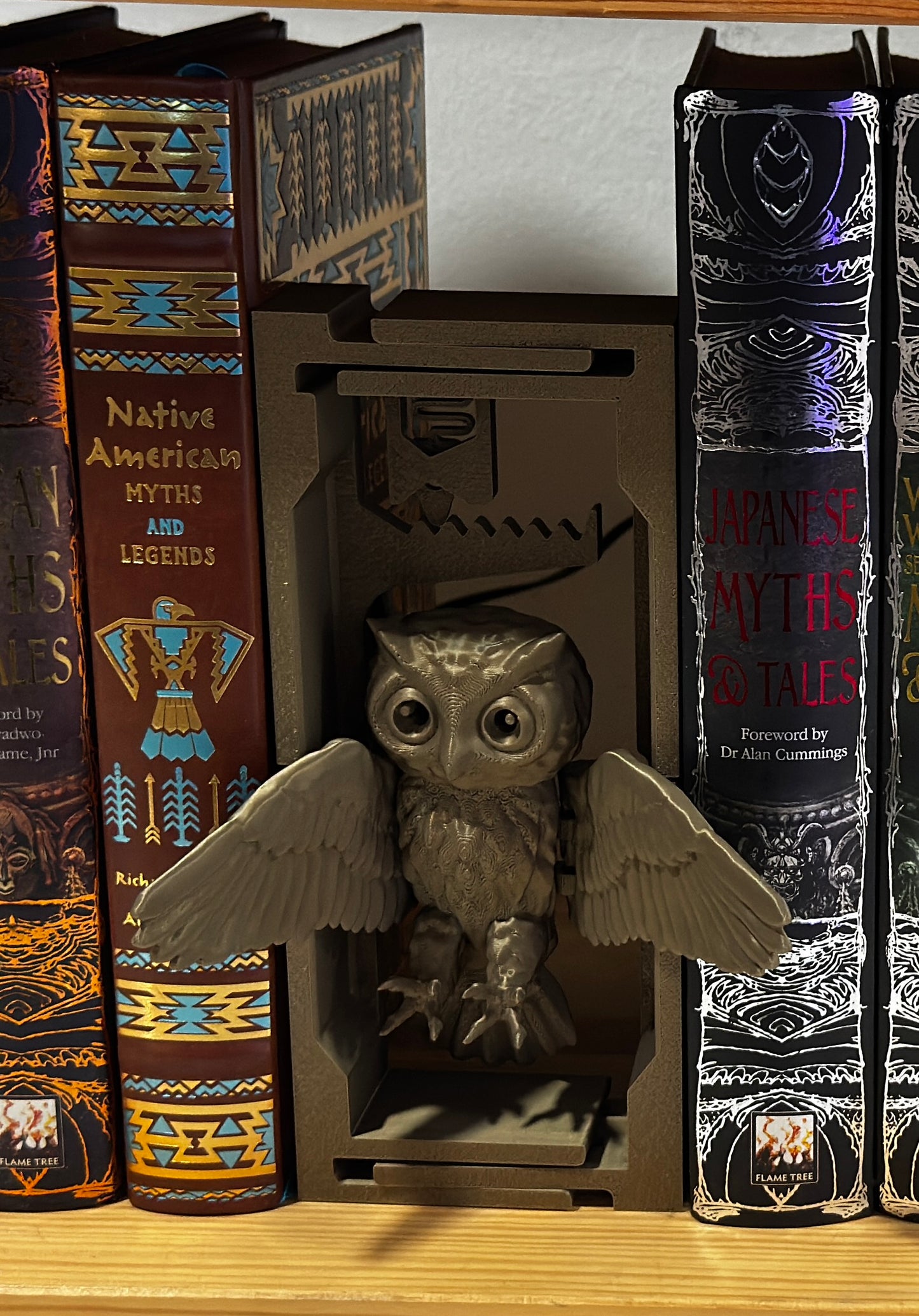  3D-printed adjustable owl book nook filling a gap on a wooden bookshelf.